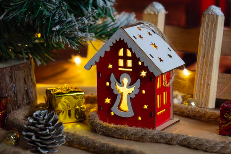 Rotes Adventshaus aus Holz mit Engel
