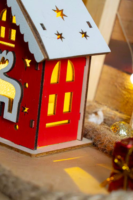Rotes Adventshaus aus Holz mit Hirsch